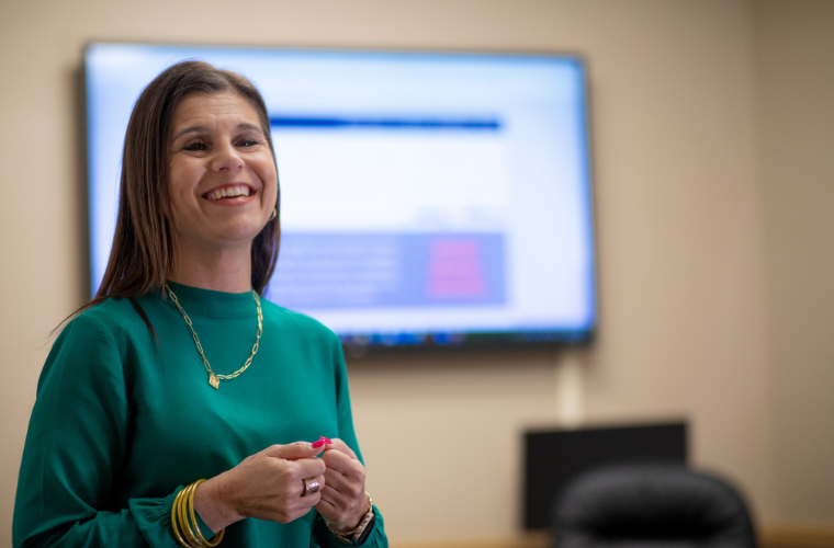 Cancer registrar Lea Guidry is pictured in front of a presentation screen.